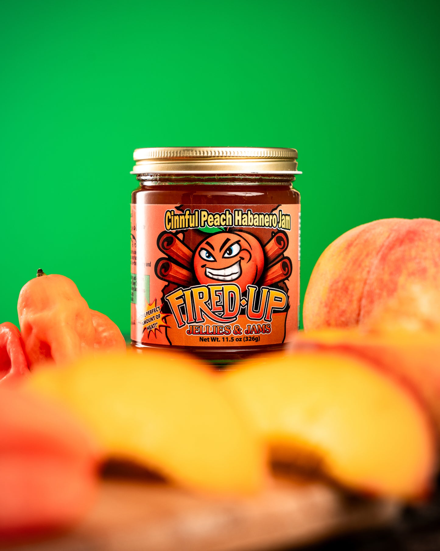 Cinnful Peach Habanero Jam nestled with peaches and green background