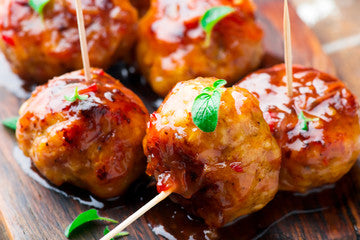 Cinnful Peach Habanero Jam glazed meatballs with toothpicks on a wooden board